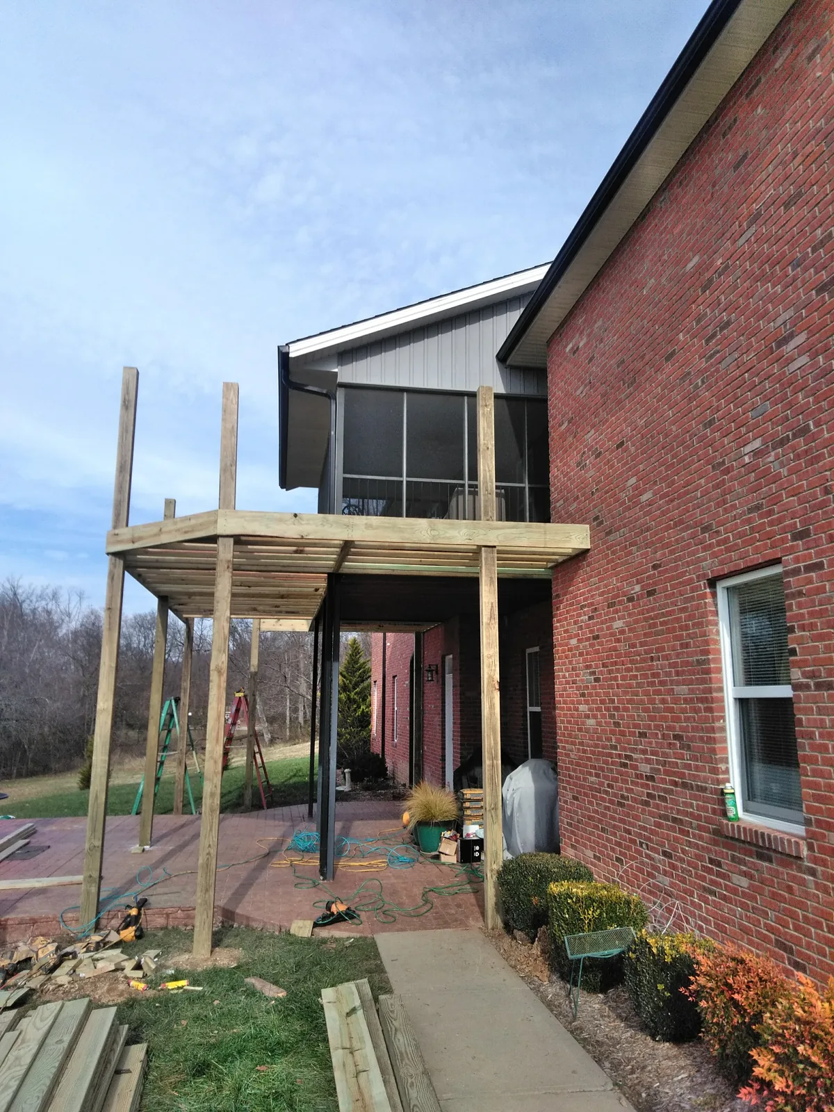 Wood deck framing and posts alongside a brick home